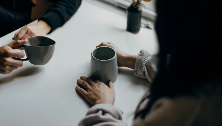 Two people talking over cups of tea